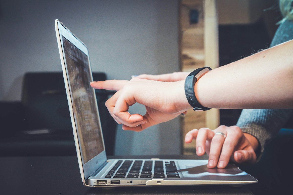 A teammate pointing something out on a laptop during a conversation.